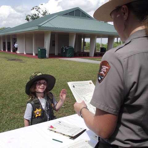 A young Junior ranger wearing a vest with numerous junior ranger badges