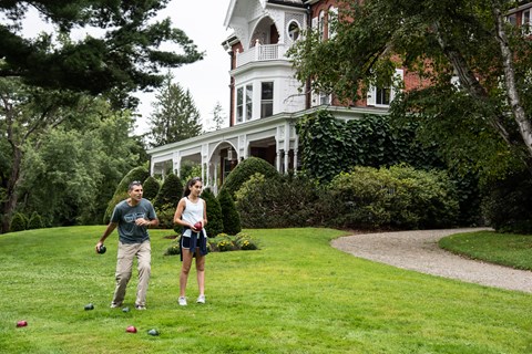 Two park visitors play bocce ball in front of the Marsh-Billings-Rockefeller mansion