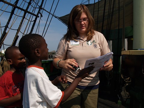 two children show a ranger their answers in the Junior Ranger booklet