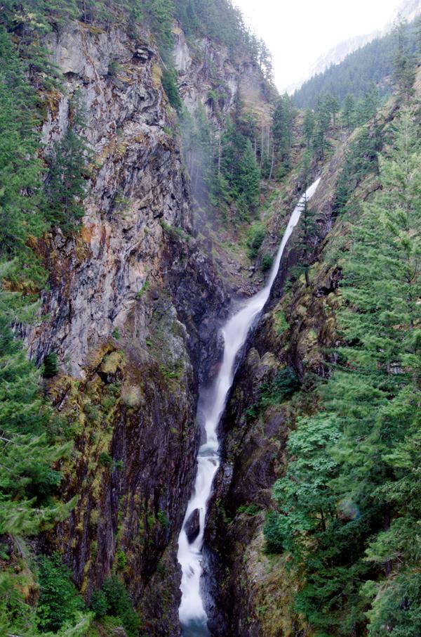 A waterfall flows through a steep, rocky gorge.