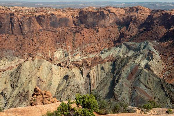 Layers of green, red, beige and orange rock are visible within a crater.