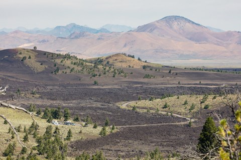 A narrow road winds through a volcanic landscape to a small parking area.