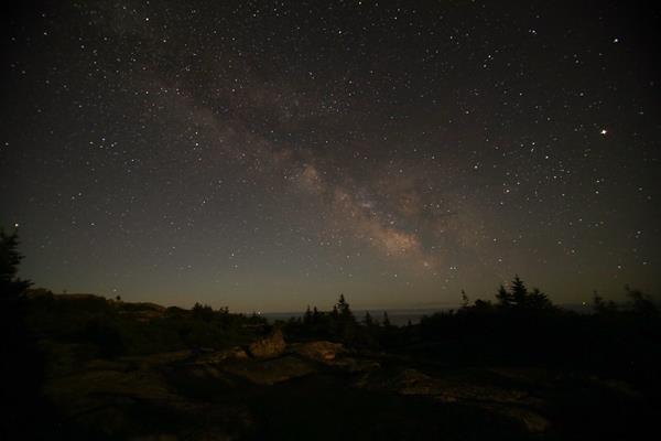 Milky way over a mountain summit and trees