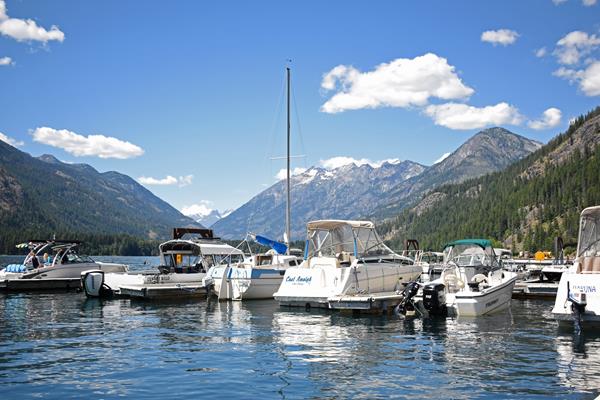 Motorboats are docked on a large lake with mountains in the background