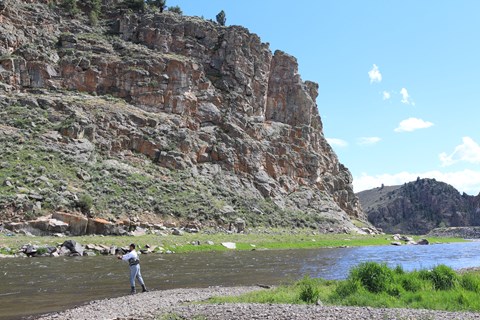 A person casting a fishing rod next to a river
