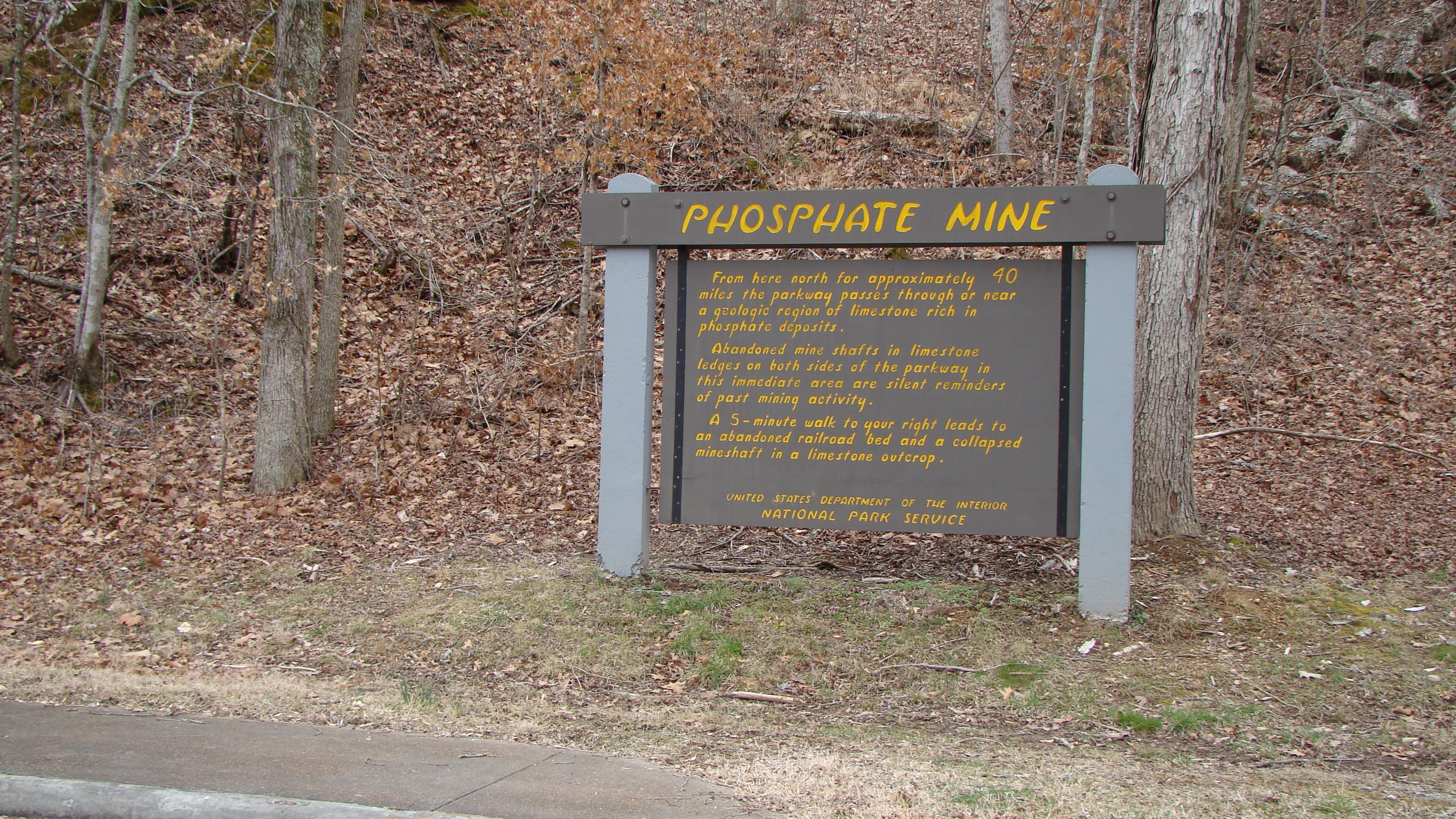 Wooden sign painted with yellow letters. Phosphate Mine is across the top