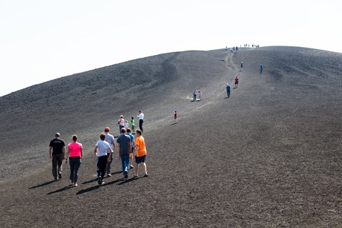 Visitors start a steep climb up a bare cinder slope.