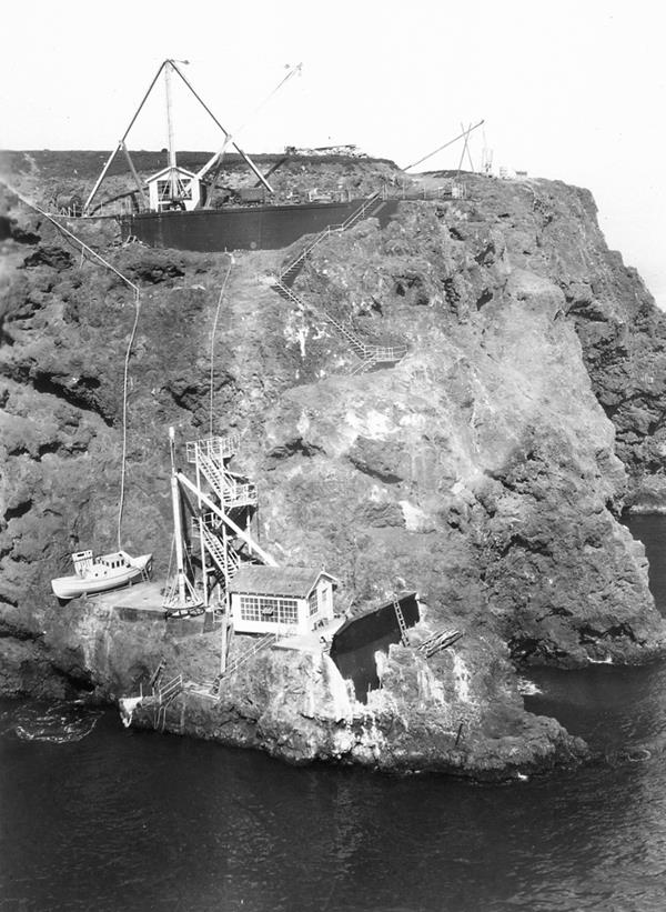 Steep cliff with stairs, buildings and boat.