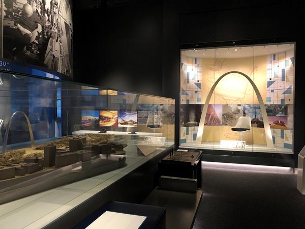 two glass cases, one holding a model of the Arch grounds and one a large model of the Arch structure