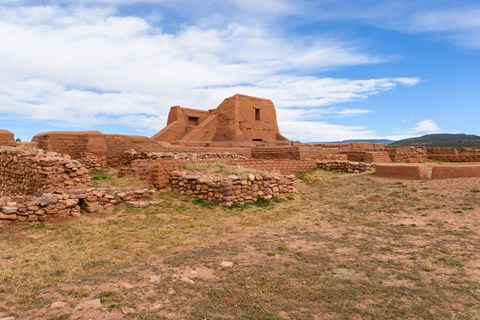 Adobe ruins with stone walls, under a blue sky in a desert setting.