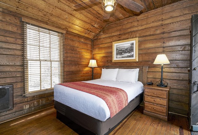 The interior of a rustic cabin with wood walls and a bed.