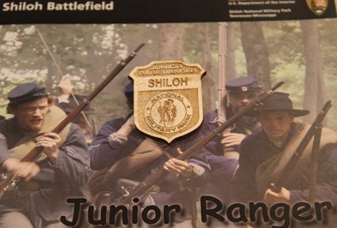 A wooden Junior Ranger Badge sits on Junior Ranger booklet
