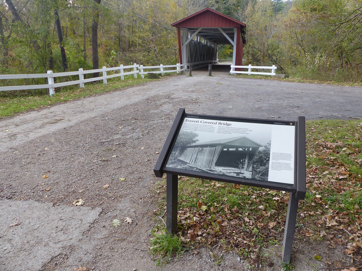 Graphic panel shows a historic photo of the red and white covered bridge beyond.