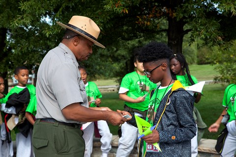 A park ranger hands a 4th grader his Junior Ranger badge.