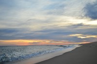 A streak of orange at the horizon is sandwiched between gray sky and ocean.