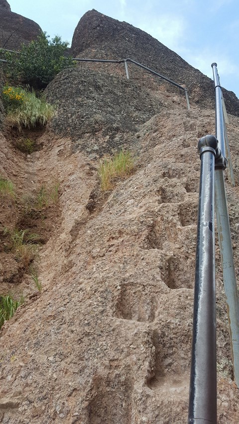 Handrail and series of foot notches carved into steep rock.