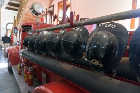 a historic fire truck with helmets mounted on the side