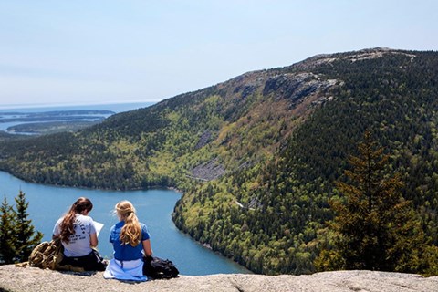 Two hikers sit on the bald granite summit of North Bubble studying a map.