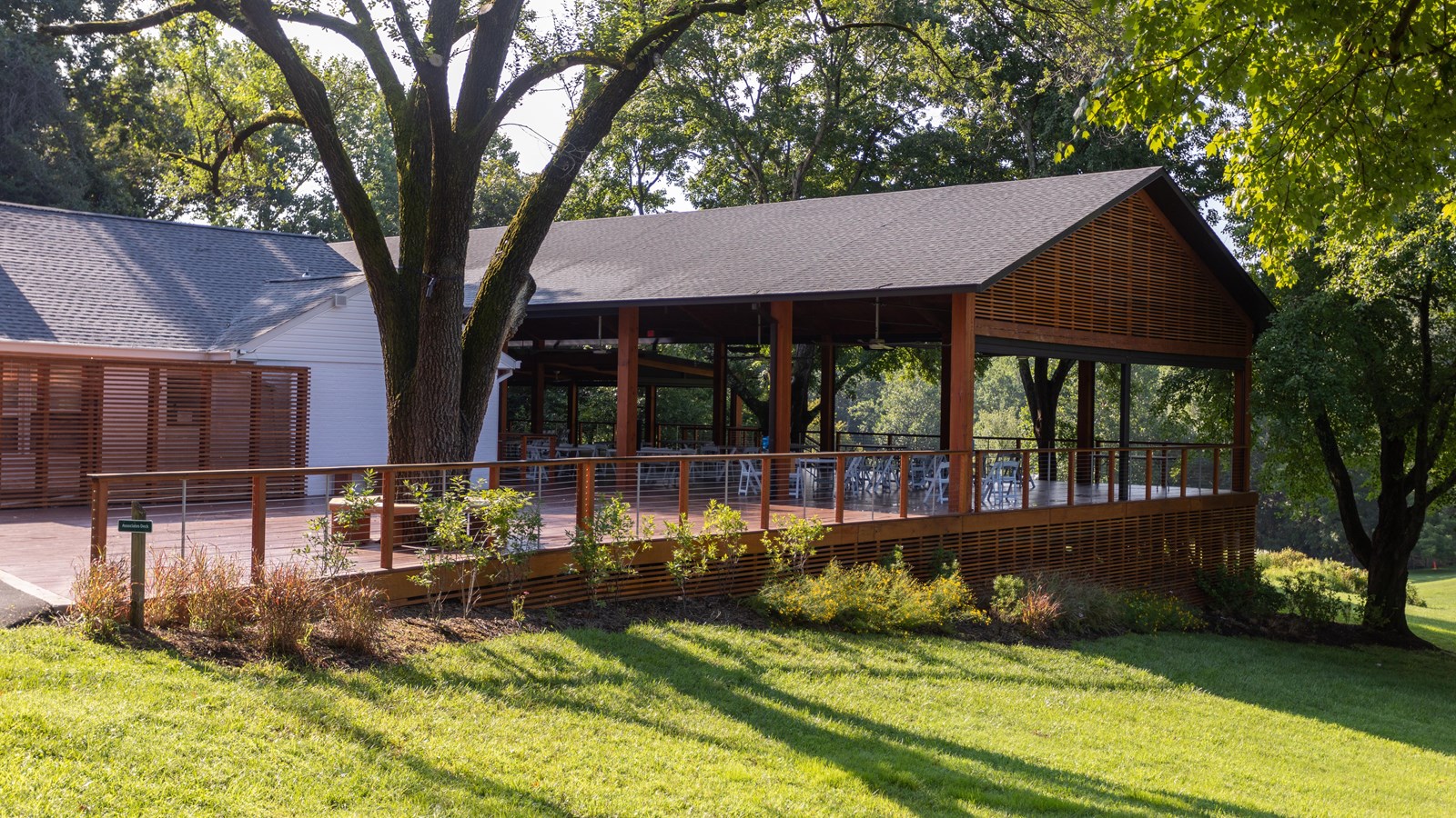 A covered pavilion structure with a sloping grass lawn beside it.