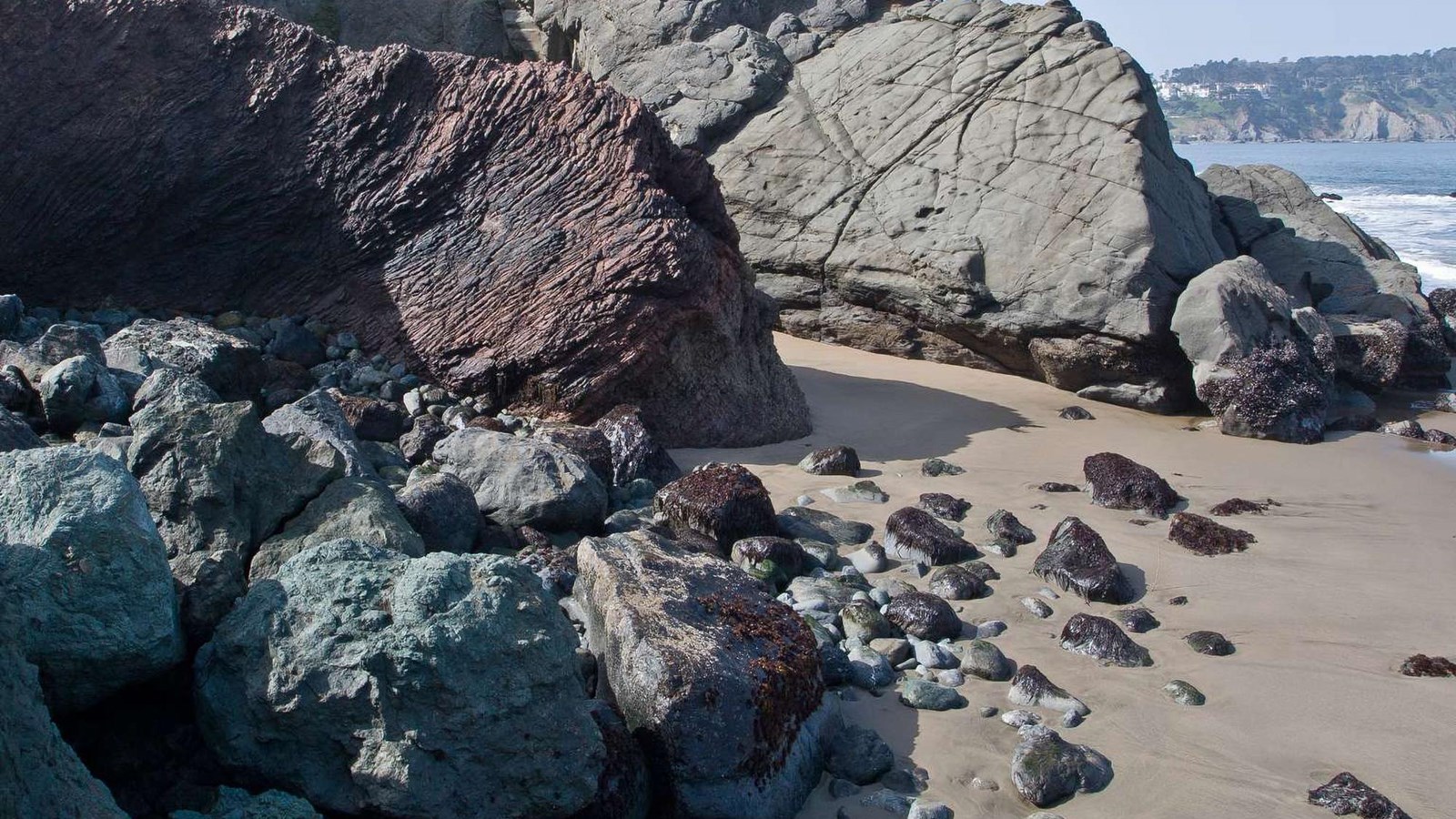 A bluff composed of blocks of bedded red chert and massive sandstone with blue-green serpentinite.