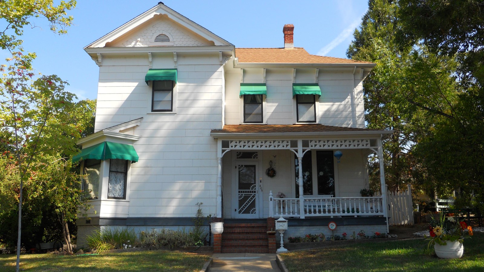 White two story house with green awnings over the windows