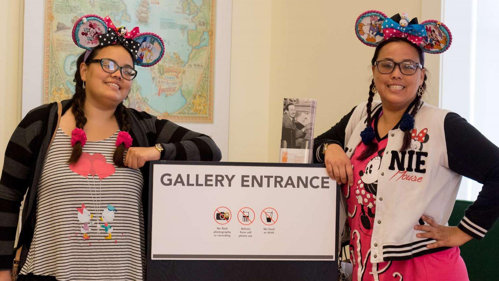 Two smiling staff members wearing Mickey Mouse ears.