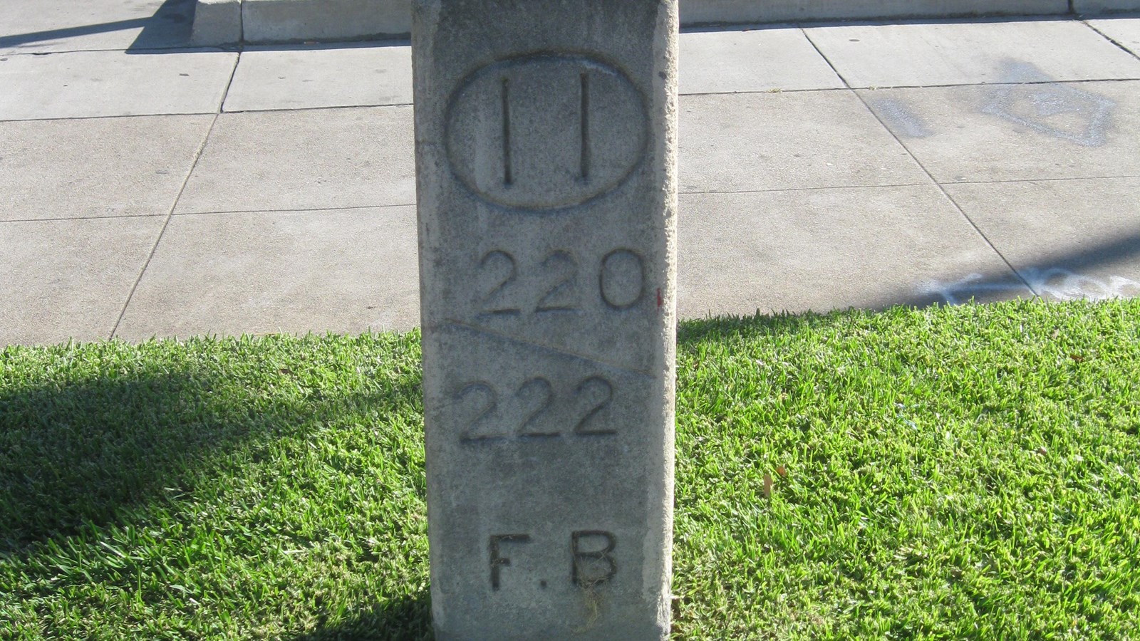 A rectangular concrete marker next to the road reads 