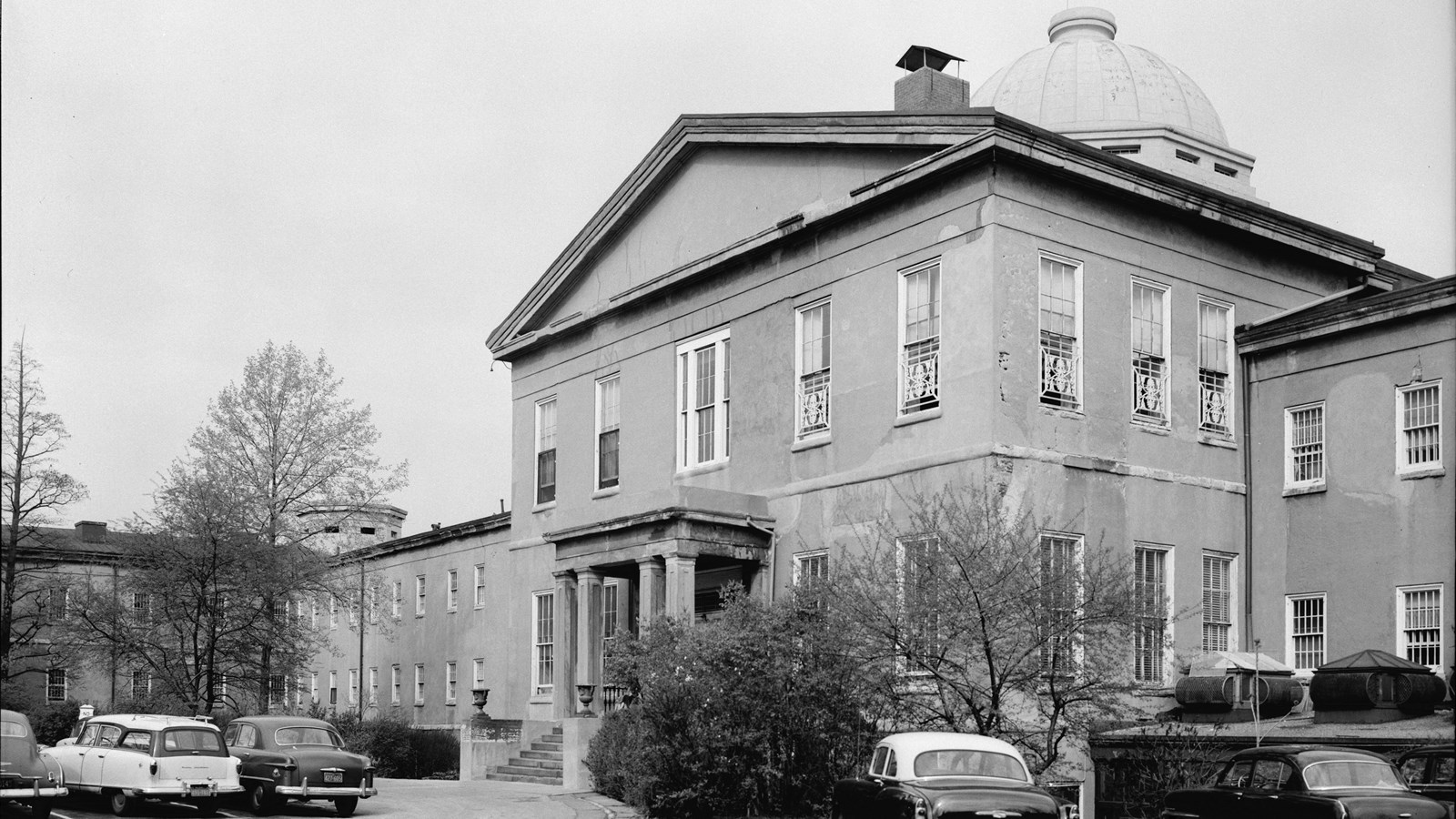 Black and white photo of a large stone building with a dome on the roof