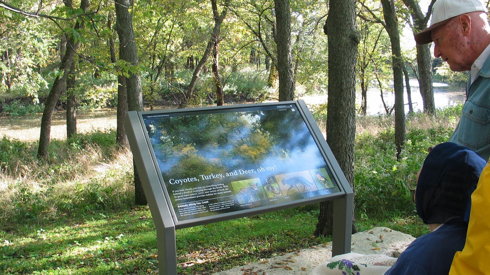 Visitors viewing one of the waysides along the Bottomland Nature Trail.
