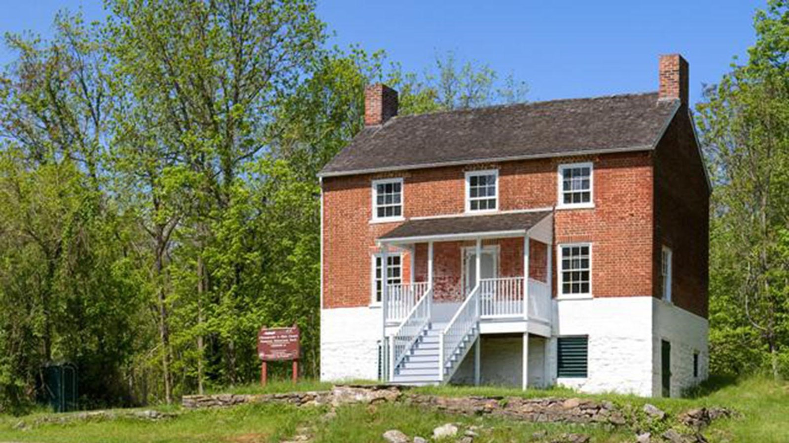 A three-story, brick lock house sits on a small hill.