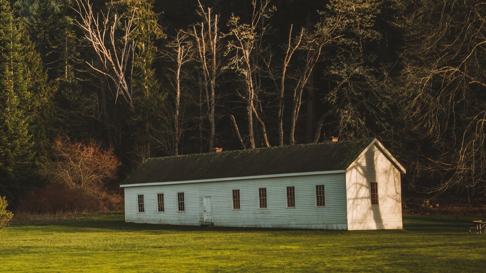 Color photo of a white wooden building in a field