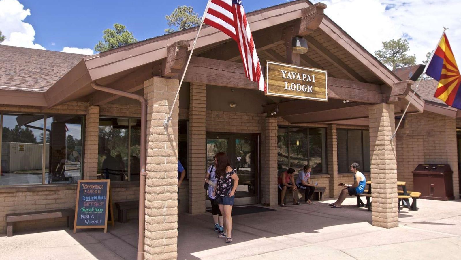 several people stand by the entrance to a modern lodge with a gabled roof