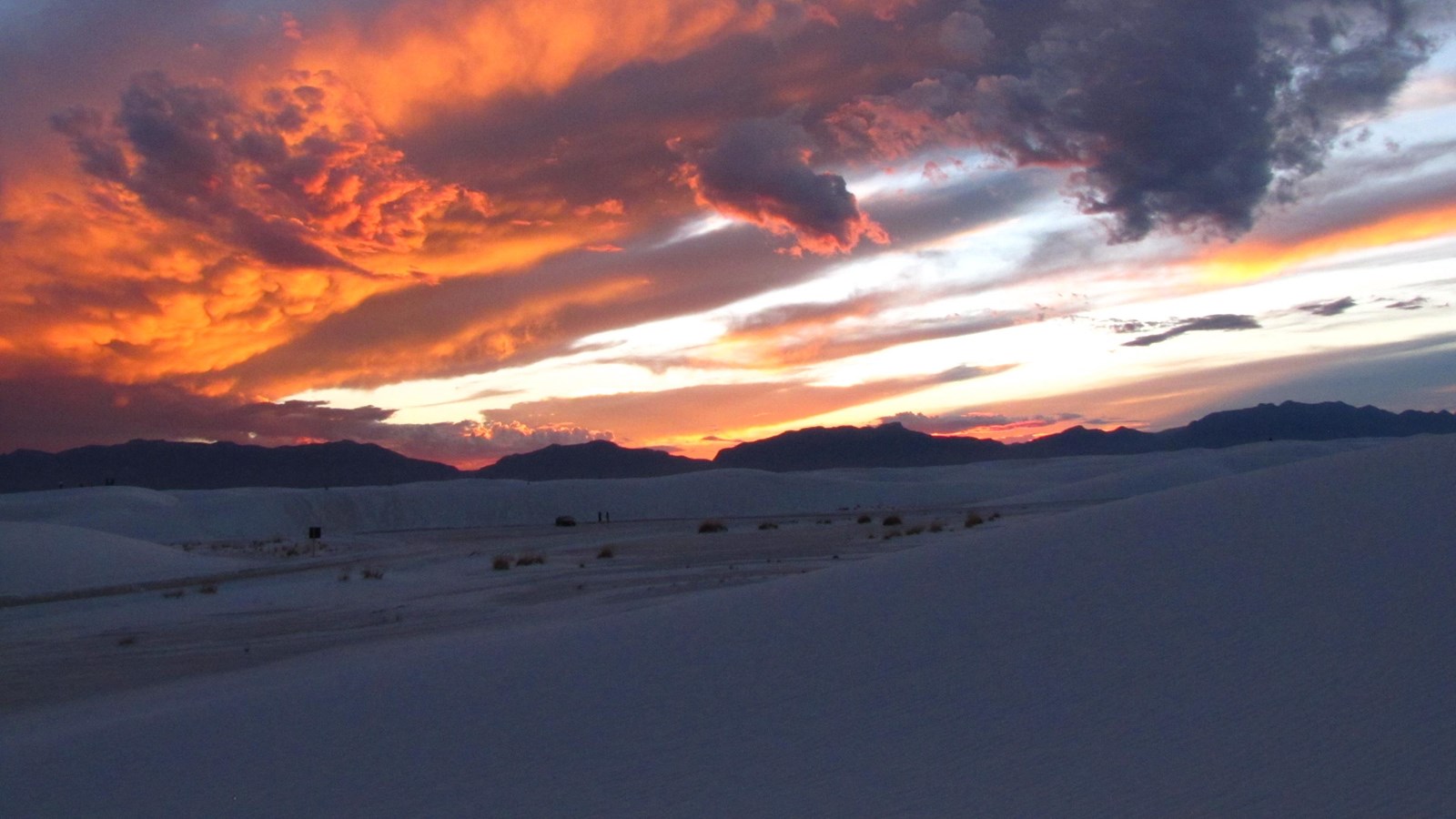 White sand dunes with mountains in the distance at sunset