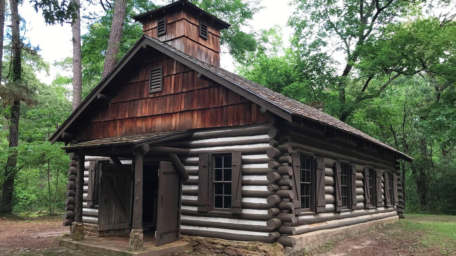 A wood cabin in a green forest.