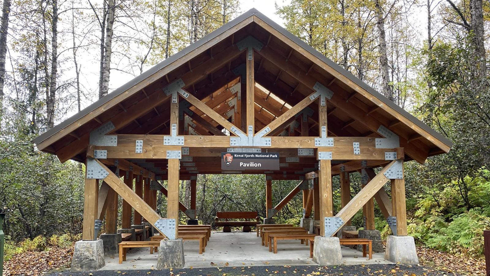 A covered wooden building. The building is open on four sides. Underneath the cover are benches