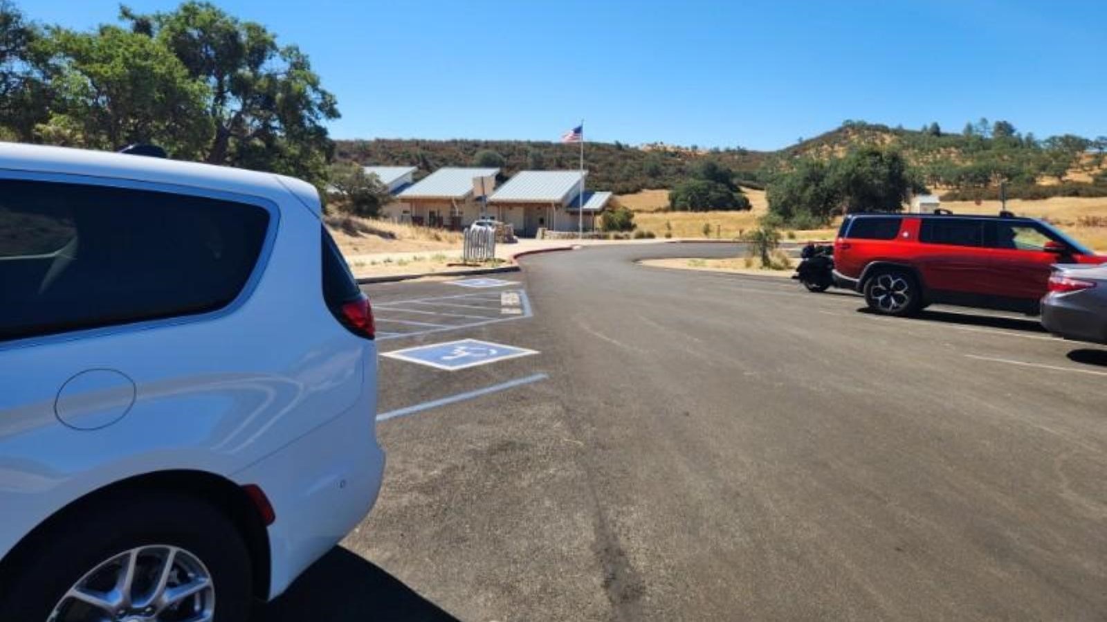 Vehicles parked in a paved parking area near a visitor center.
