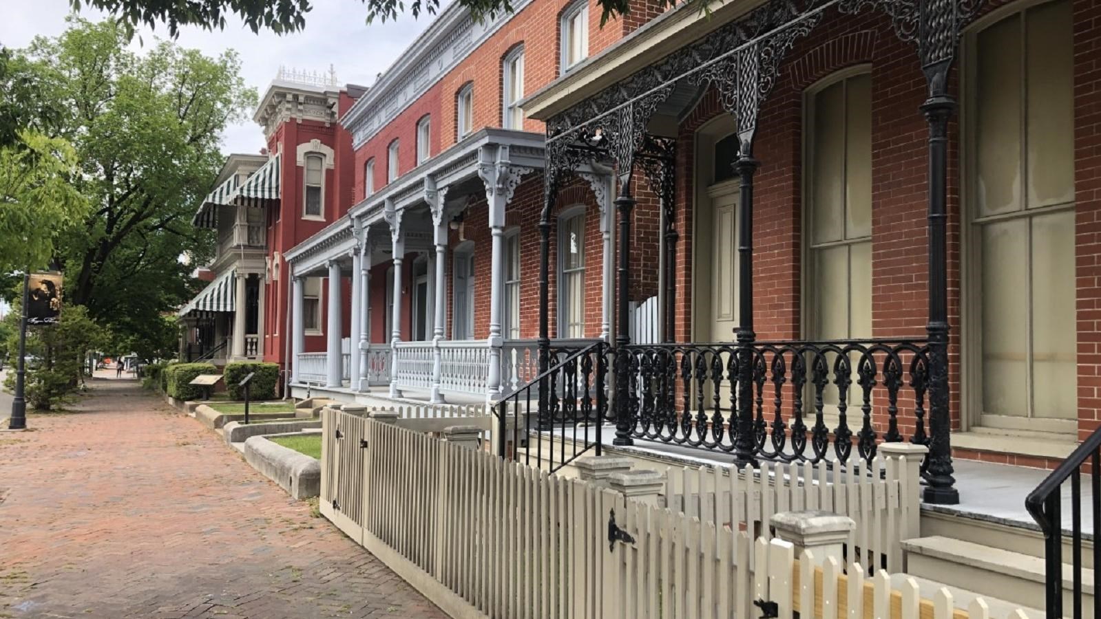 Several two-story red-brick buildings line Leigh Street, with porches in front of each home