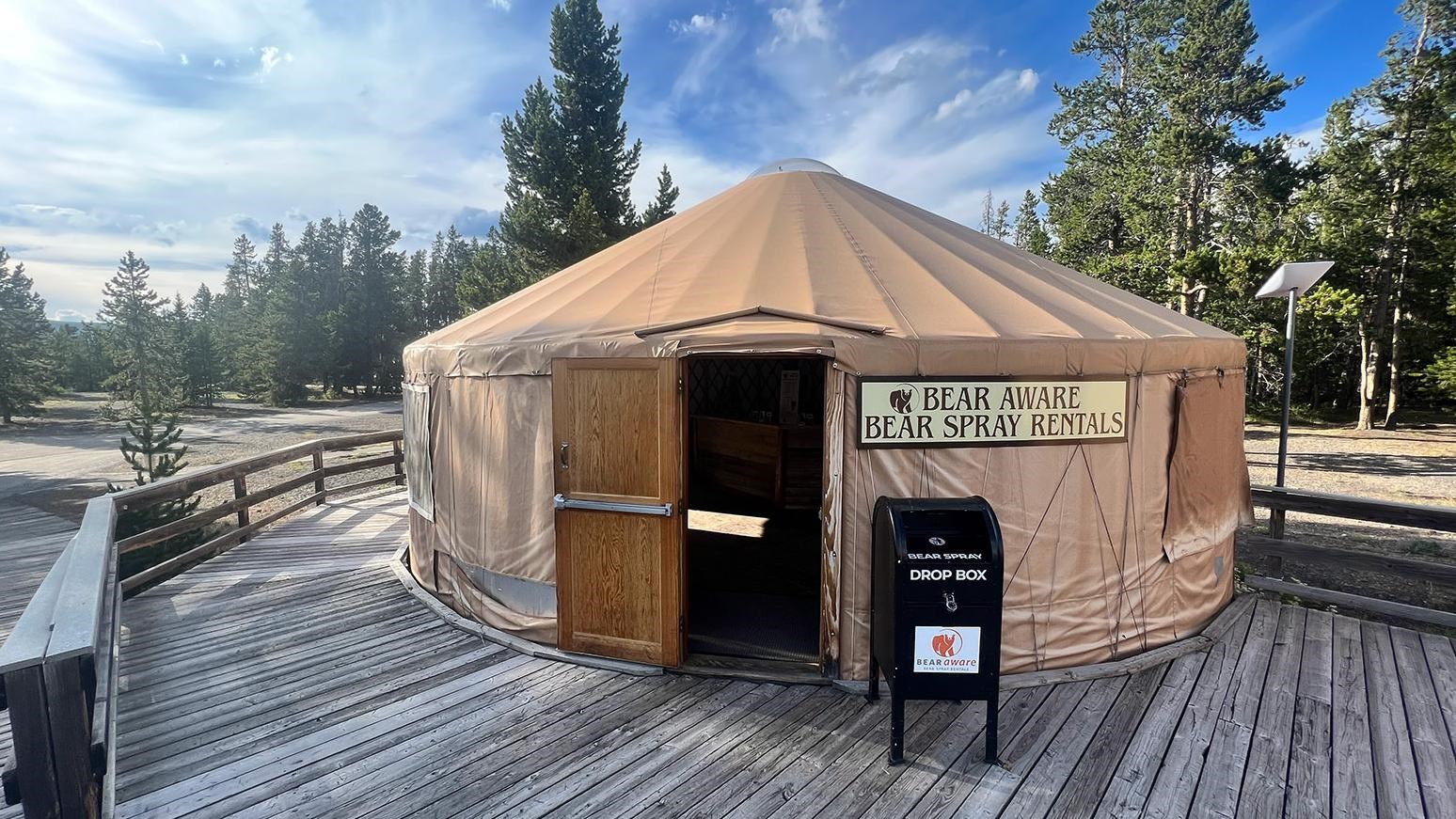 Bear Spray Rentals sign on entry to canvas yurt on a wooden deck