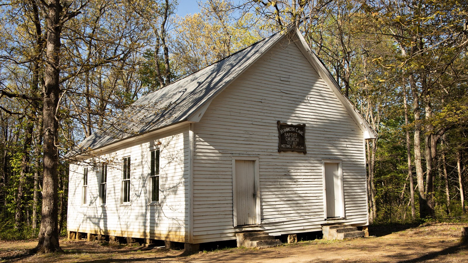 a white, one-story building in a forest