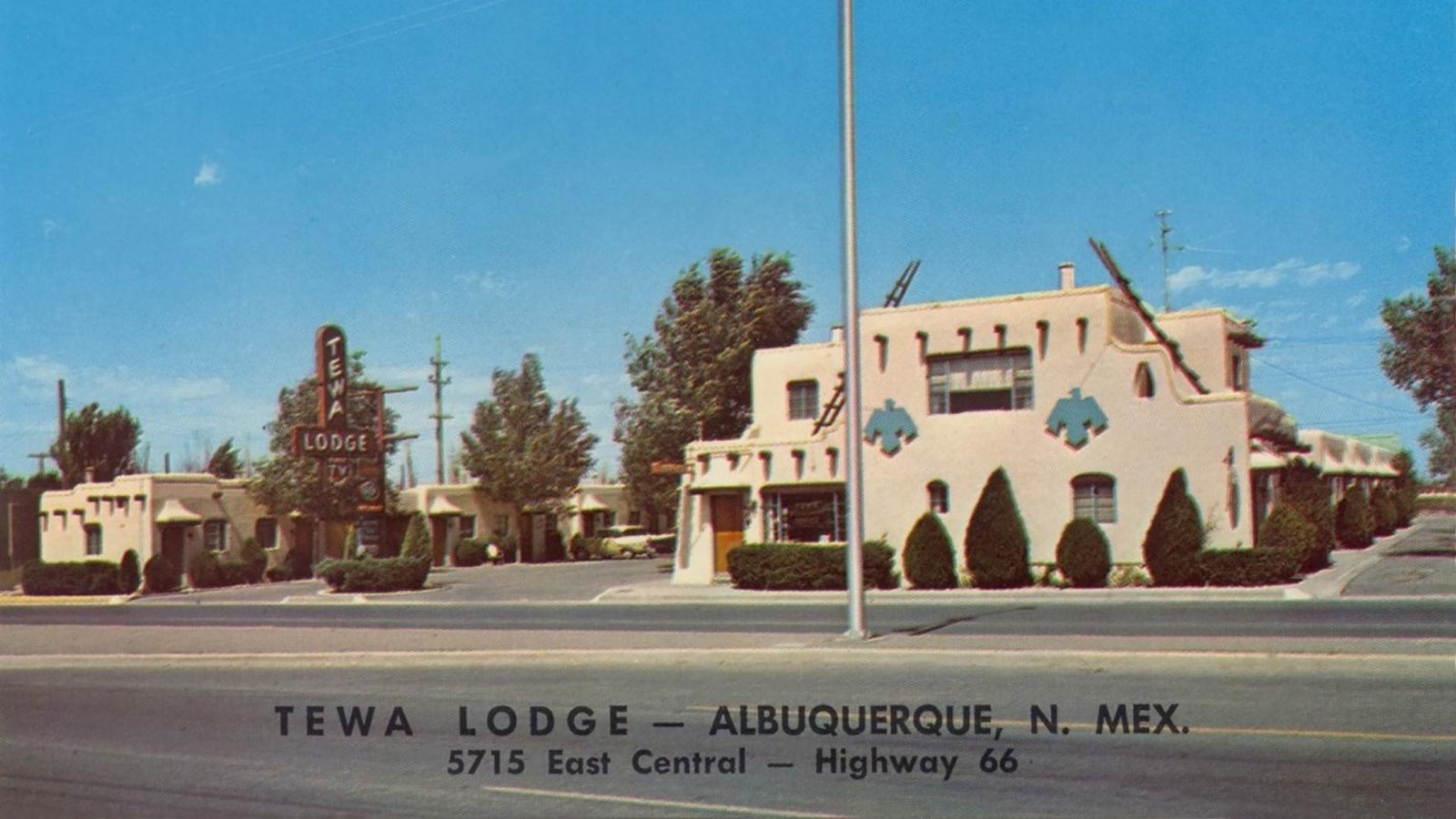 A historic postcard of a white stucco building with teal detailing; it reads
