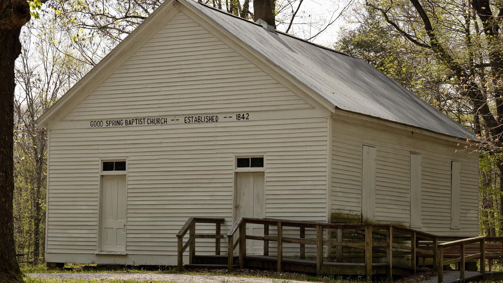 a white, one-story building in a forest