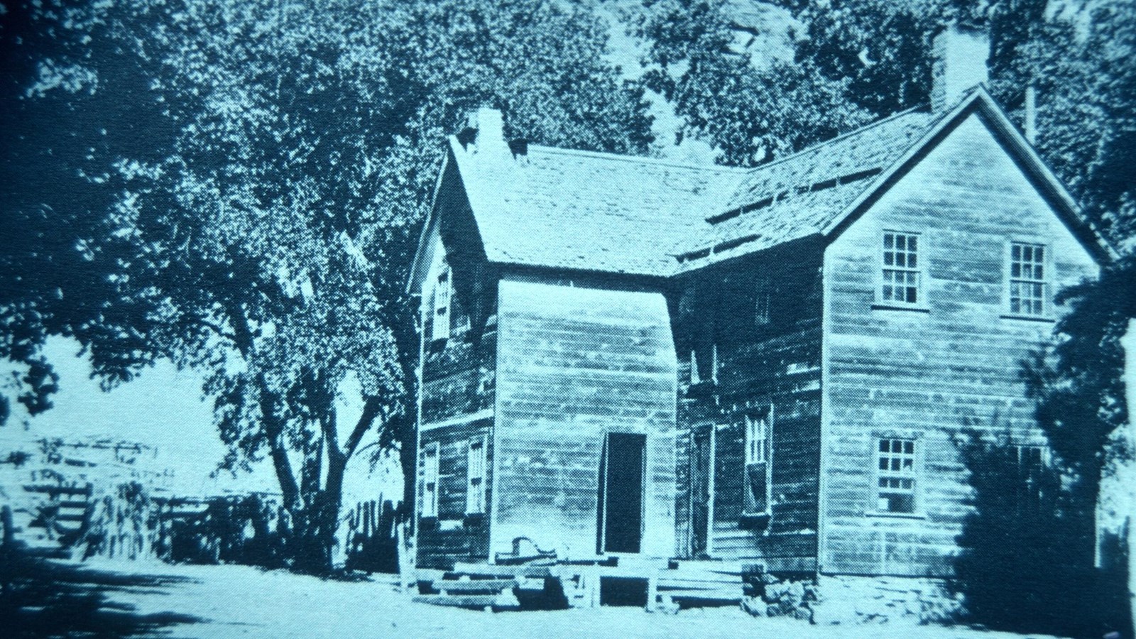 Two story, wooden plank home with a small porch. 