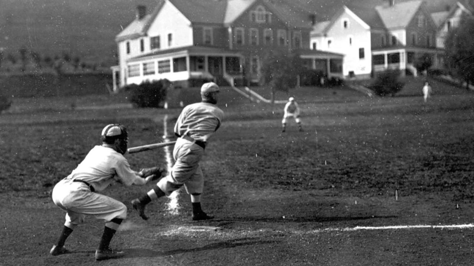 Two soldiers at home plate, playing baseball in Fort Baker.