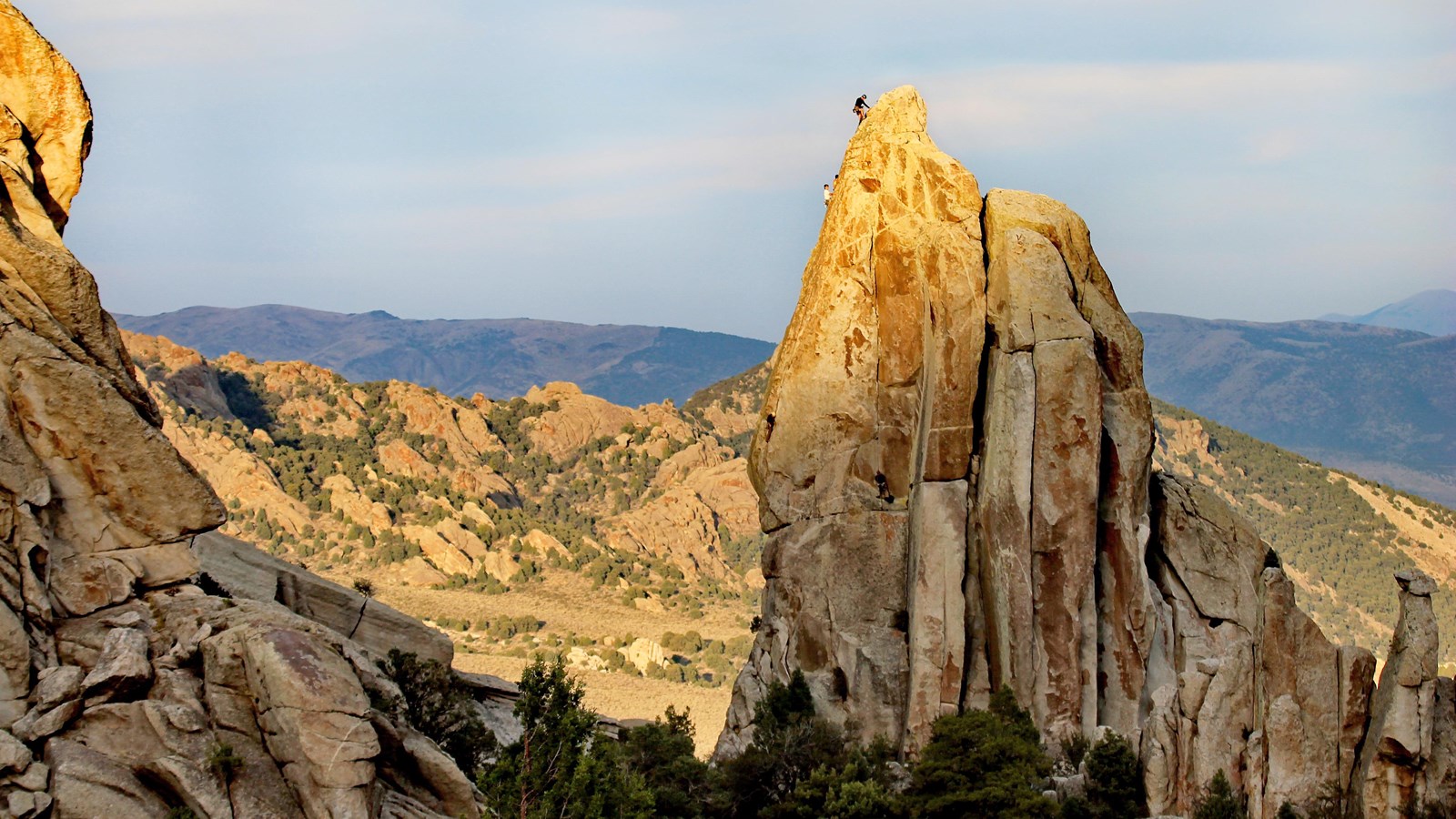 Climbers can be seen ascending the impressive granite spire as fading sunlight grazes the land.