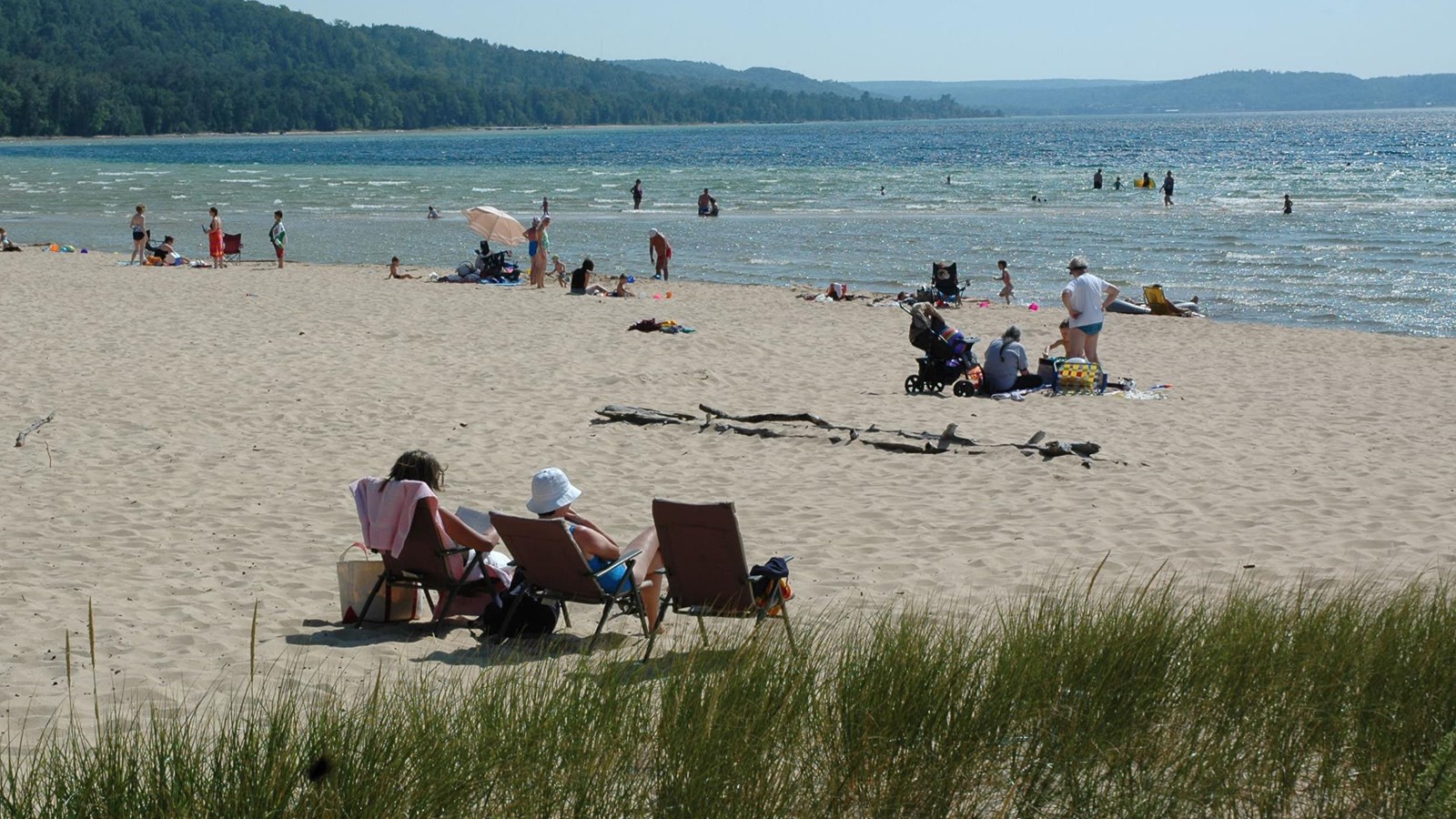 Visitors sunbathing on the beach and swimming in the water.