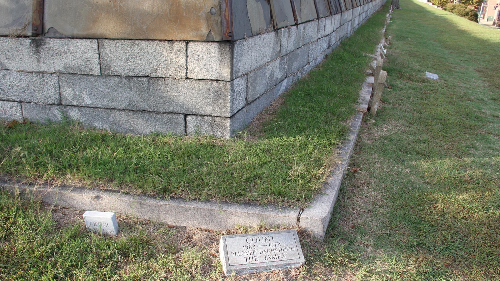Grave markers at base of breast-height wall coming to a point at the center and receding back  