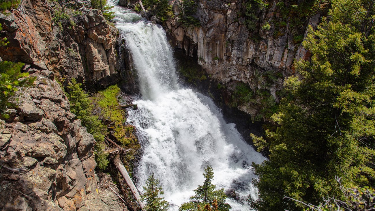 A two-tiered waterfall surrounded by columnar basalt as viewed from above.