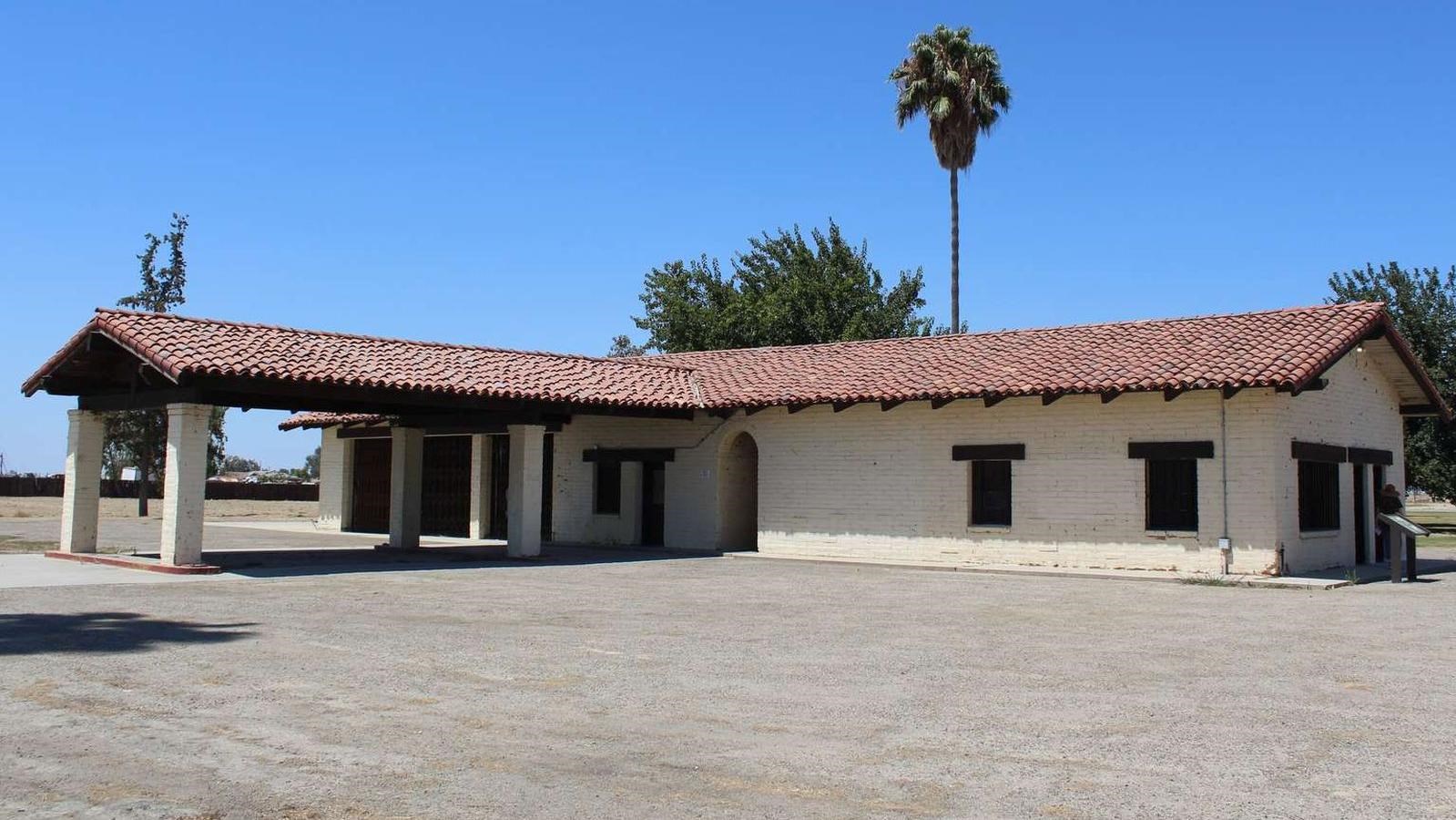 A white brick building with a red tile roof.