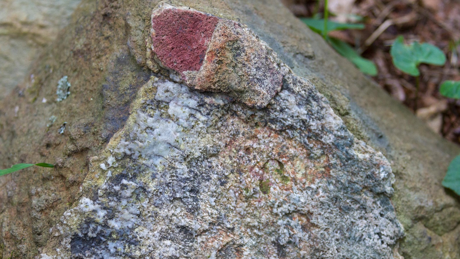 A triangular stone face boasts vibrant colors of red, white, orange, and blue.