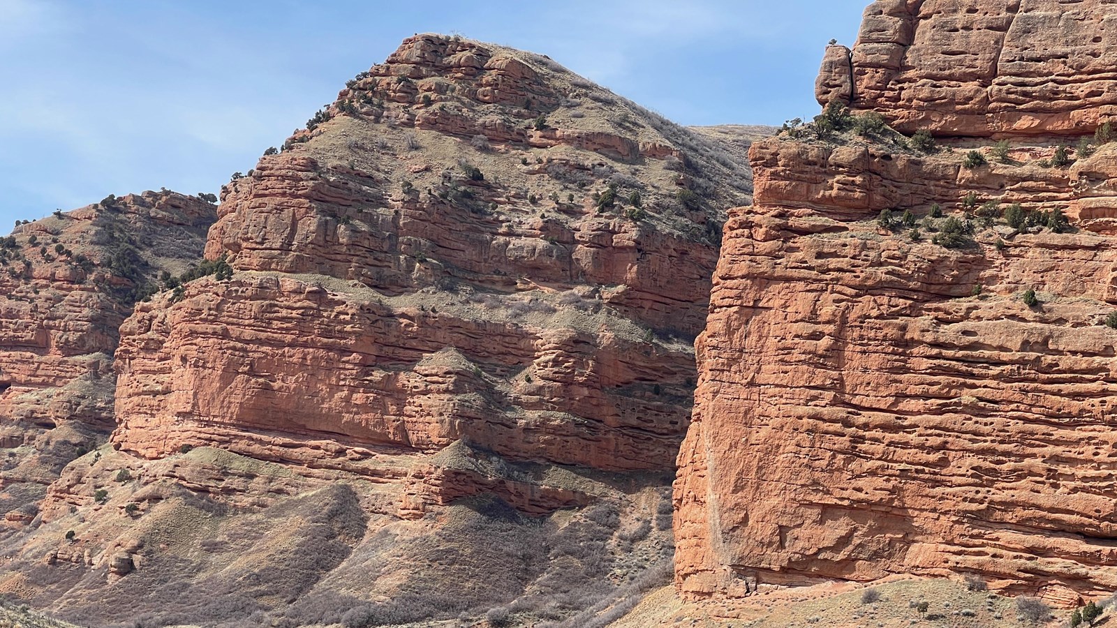 A rock monolith, littered with small holes and a road to the bottom right of the photo.